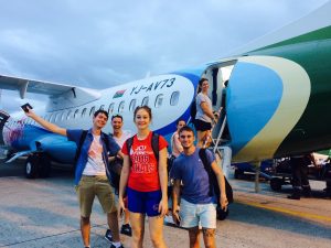 six students standing in front of an airplane waiting to board