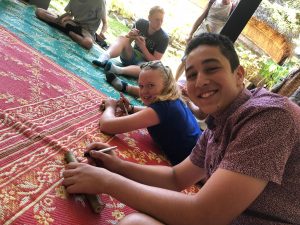 three international students sitting on the floor leaning on an embroidered carpet