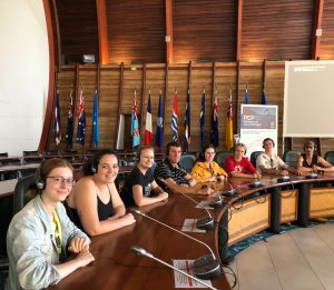 Group of eight caucasian students sitting in conference room with headphones and microphones at South Pacific Communities centre in New Caledonia.