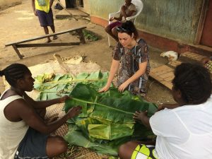 Islander women sitting on the ground and folding banana leaves