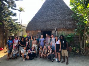 Large mixed group in front of traditional kanak hut