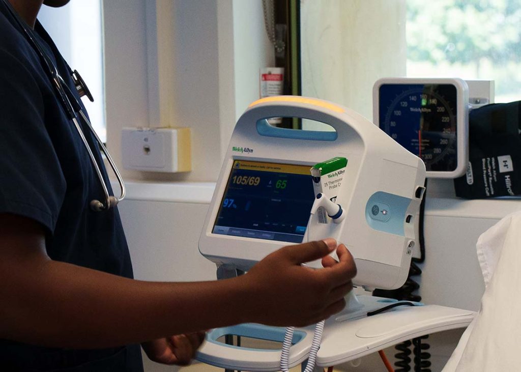 A close-up photo of a nurse using the vital signs machine.