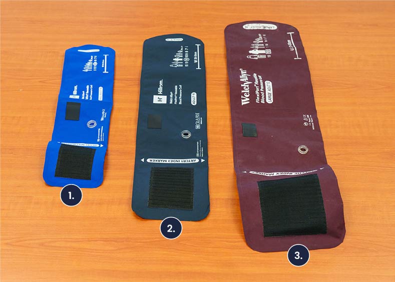 A photo of three blood pressure cuffs on a table. Shown from left to right are sizes small adult 10, adult 11, and large adult 12.