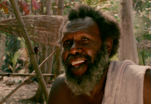 Eddie Koiki Mabo, smiling, sitting in front of a traditional fish trap on the island of Mer