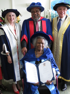 Bonita, seated with her honorary doctorate, with Martin Nakata and other dignitaries standing behind her