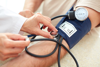 A persons arm is extended with a medical professional using a blood pressure instrument gauge to check the patient's blood pressure.