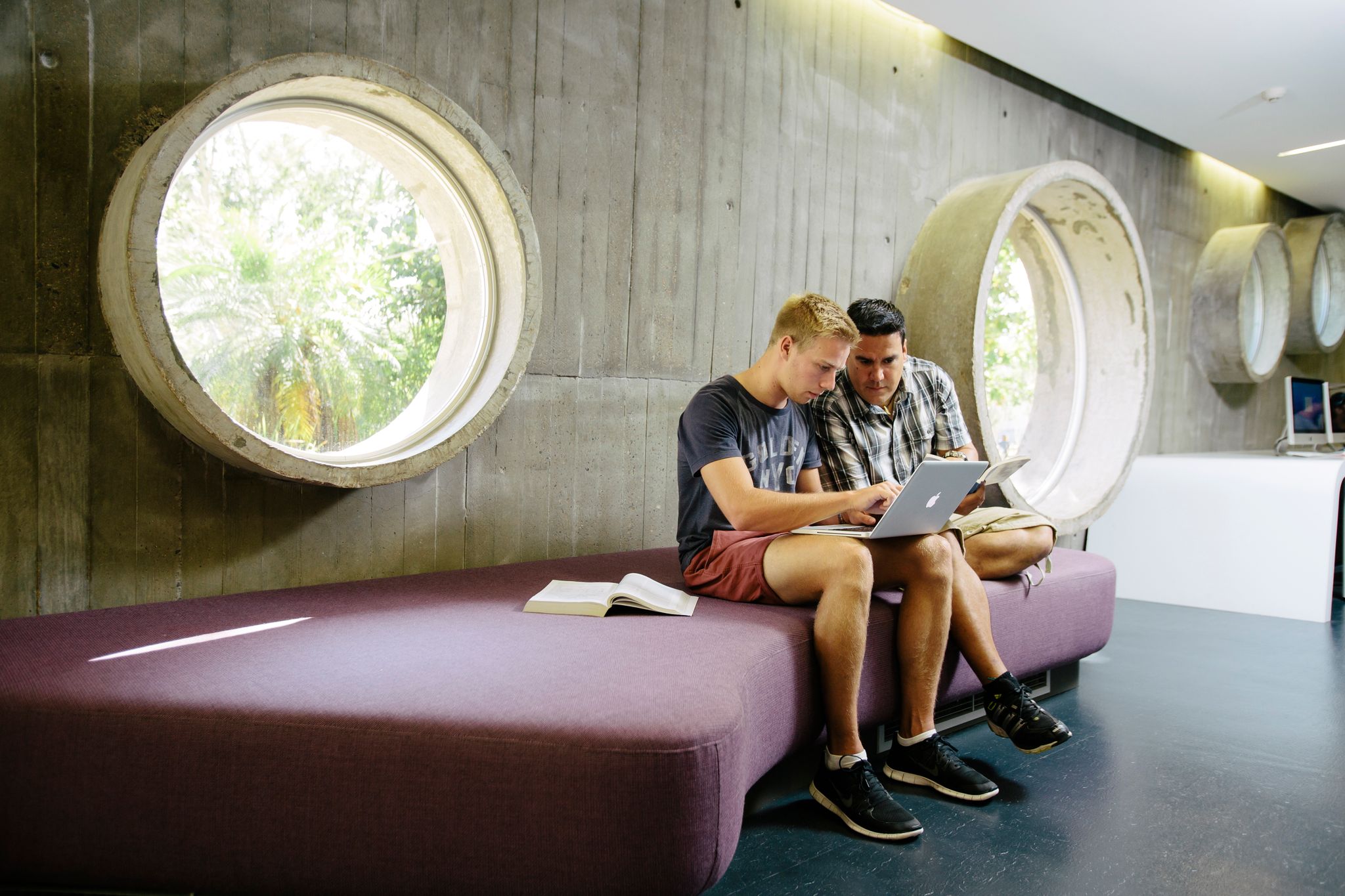 Two students sit focussing on a laptop in the library