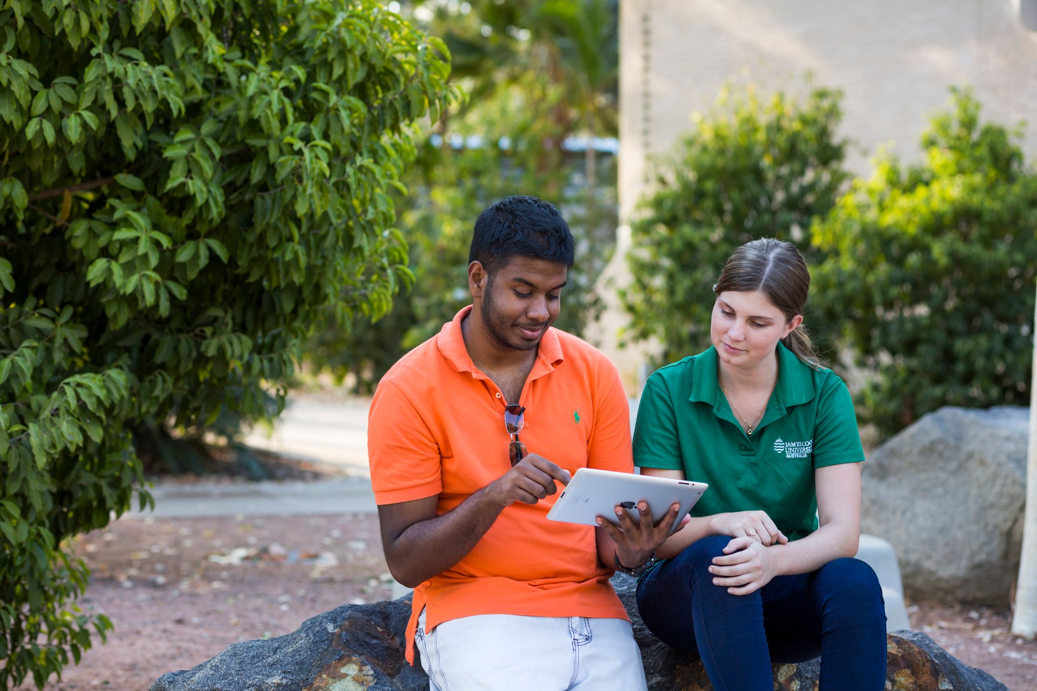 Two students sitting together looking at an iPad