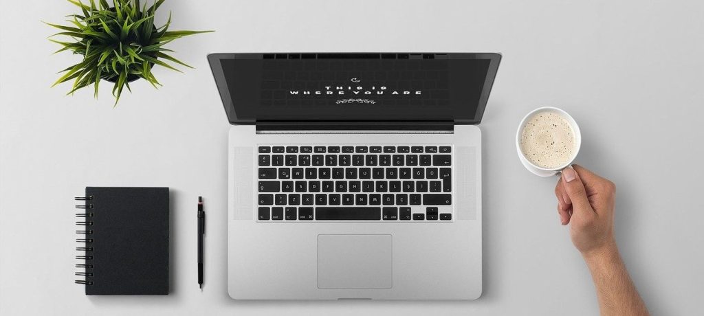 Laptop, pen, notebook and coffee on a desk